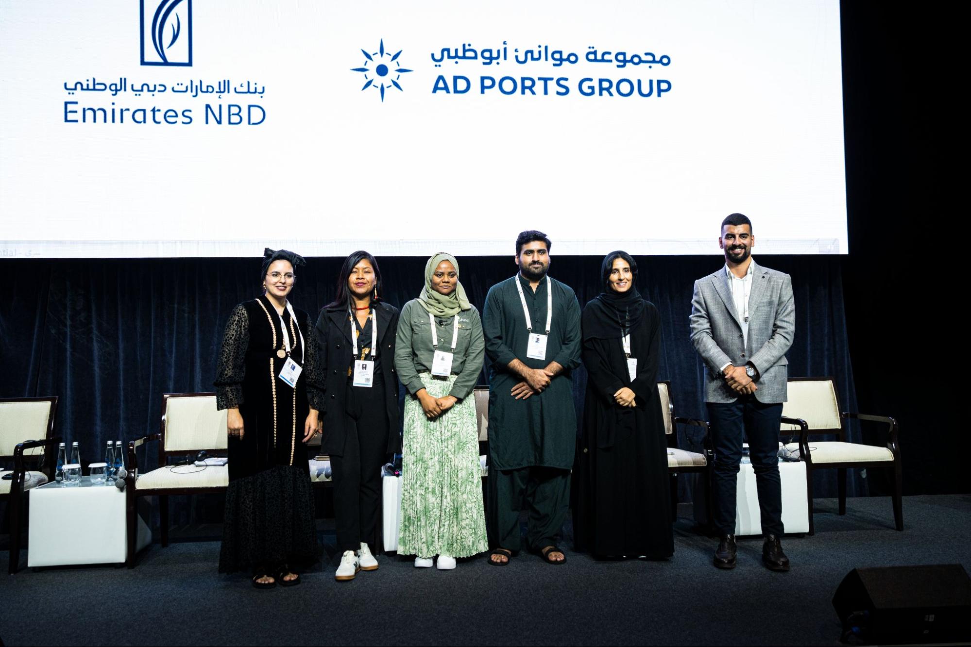 Six well-dressed young people on a stage.