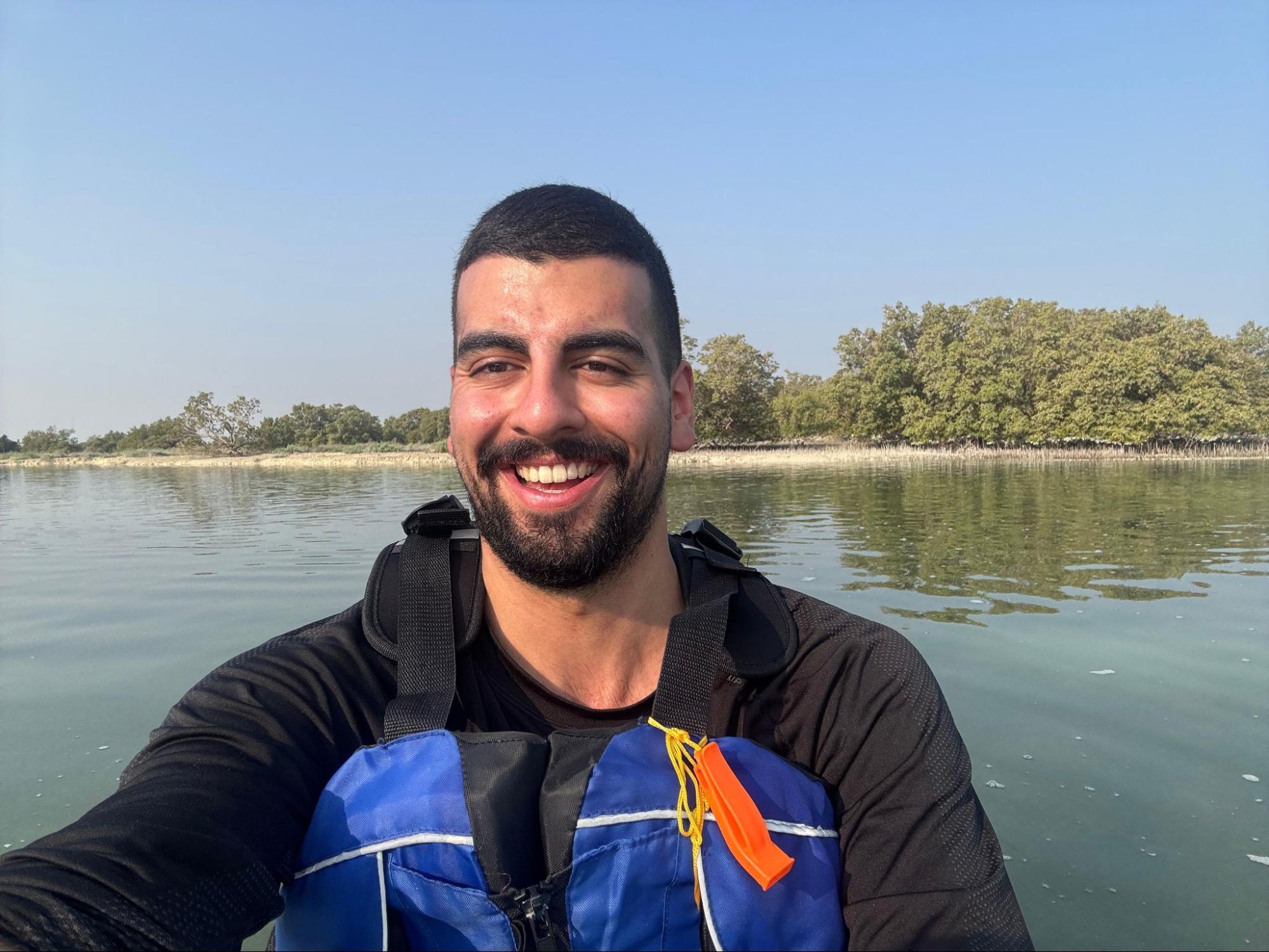 A young man smiling in a kayak out on the water.