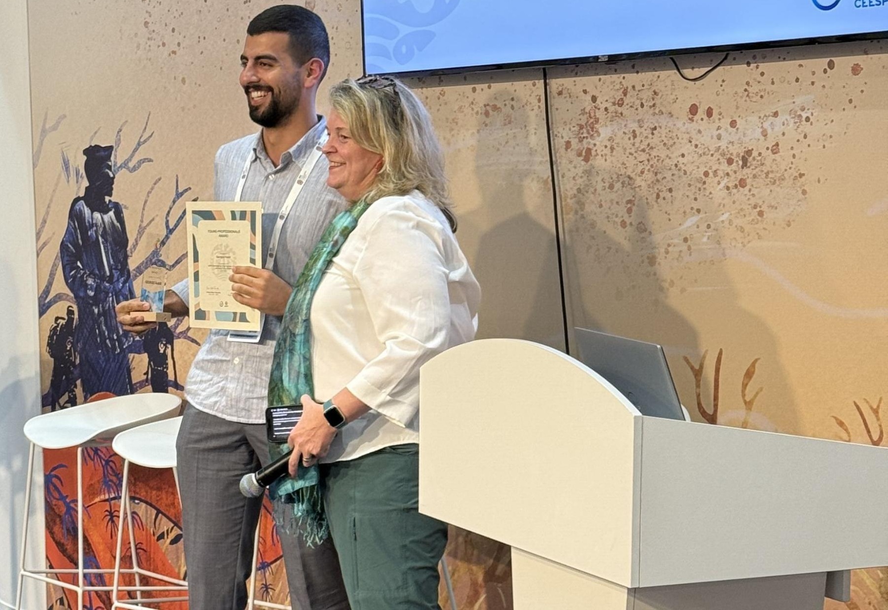 A young man standing next to an older woman holds a certificate.