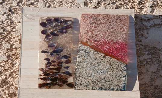 Two eye-catching rectangular blocks of material. The left one looks like the shells of mussels suspended in gelatin; the right looks like red and black gelatin with ground-up seashells inside meeting along a diagonal.